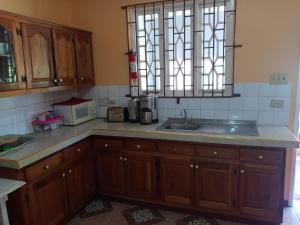 una cucina con armadi in legno, lavandino e finestra di Twin Court Retreat a Port Antonio