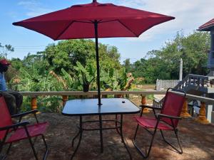 a table with a red umbrella on a patio at Twin Court Retreat in Port Antonio