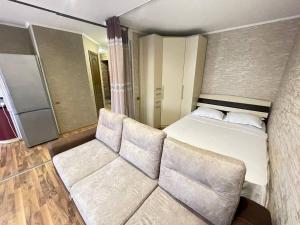 ein kleines Schlafzimmer mit einem Bett und einem Sofa in der Unterkunft 1-комнатная квартира - студия в центре города! in Petropawlowsk