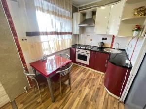 a small kitchen with a red table and a stove at 1-комнатная квартира - студия в центре города! in Petropavlovsk