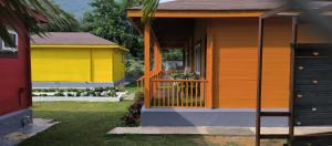 een geel en oranje huis met een veranda bij The Laughing Woods in Kotagiri