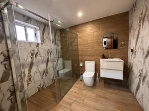 a bathroom with a shower and a toilet and a sink at The Fjord at Libi Apartment in Accra +39 photos