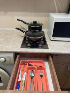 a pot on a stove with utensils in a drawer at 1-комнатная квартира в центре! in Petropavlovsk