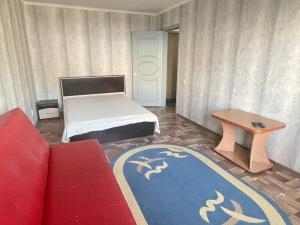 a room with a bed and a couch and a table at 1-комнатная квартира в центре! in Petropavlovsk