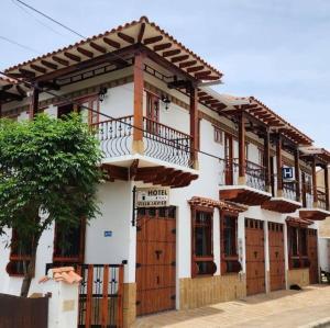 een wit gebouw met houten deuren en een balkon bij Hotel Villa Javier VDL in Villa de Leyva