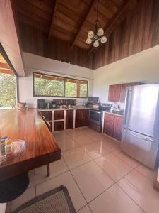 a large kitchen with a table and a refrigerator at Casa areno lodge in Bijagua
