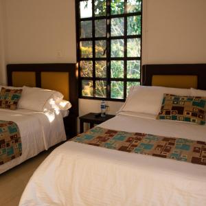 a bedroom with two beds and a window at Hotel Campestre El Triunfo in San Agustín