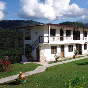 a white house with a balcony and a yard at Hotel Campestre El Triunfo in San Agustín