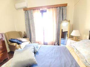 a bedroom with a bed and a chair and a mirror at Poli House Family Villa W/ Pool in Corfu Town
