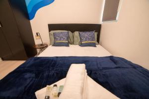 een slaapkamer met een groot bed met blauwe lakens en kussens bij Spacious and Stylish 1 Bed Modern Flat in Londen