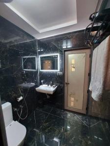 uma casa de banho com azulejos pretos, um WC e um lavatório. em Le petit chateau em Casablanca