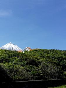 a house on top of a hill with a snow covered mountain at Casa do Areal in São Roque do Pico