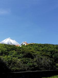 uma casa no topo de uma colina com uma montanha coberta de neve em Casa do Areal em São Roque do Pico