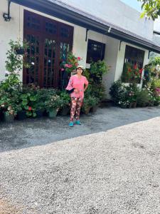 a woman standing in front of a building with flowers at PROMAX villa in Nuwara Eliya