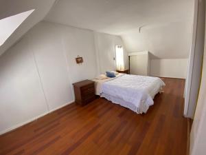 - une chambre avec un lit blanc et du parquet dans l'établissement Casa en sector residencial, à Arauco