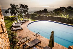 a swimming pool with lounge chairs and an umbrella at Cassia Lodge in Munyonyo