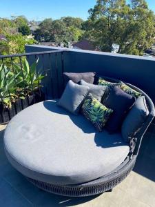 een rieten stoel op een balkon met kussens bij Chic Rose Bay Pad with HUGE outdoor sunny balcony in Sydney