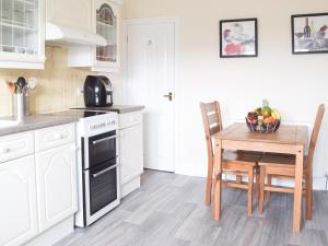 a kitchen with white cabinets and a table with a bowl of fruit at Marina Reach in Neyland