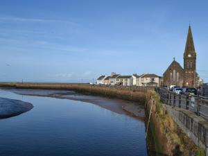 a river with a church and a clock tower at Harbour Watch in Maryport