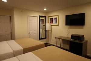 ein Hotelzimmer mit 2 Betten und einem Flachbild-TV in der Unterkunft The Hamlet Inn at Warwick in Warwick