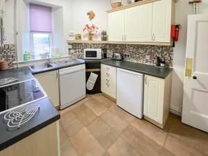 a kitchen with white cabinets and white appliances at The Gate Lodge in Latheron