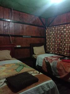 two beds in a room with wooden walls at Home stay wolokoro ecotourism in Bajawa