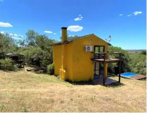 una pequeña casa amarilla sentada en la cima de un campo en Peña de Horeb, en Villa Serrana