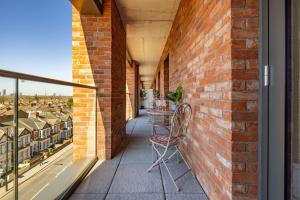 a balcony with a table and chairs on a brick wall at Wild Roses Serviced Apartments - Upton Park in London