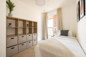 a bedroom with a large bed and a dresser at Wild Roses Serviced Apartments - Upton Park in London
