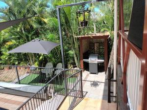 a porch with an umbrella and a grill at Tropical Poolside Retreat in Nelly Bay