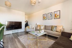 a living room with a couch and a tv at Wild Roses Serviced Apartments - Upton Park in London