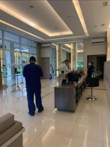 Fully furnished 1 BR Condo unit في مانيلا: رجل يقف عند مكتب في بهو الفندق