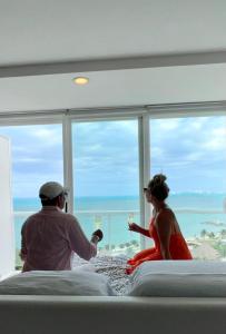a man and woman sitting in a hotel room with glasses of wine at Amara Cancun Beachfront Condo in Cancún