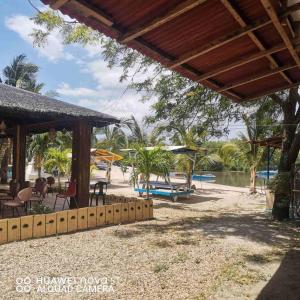 uma praia com mesas e cadeiras e um corpo de água em Binubusan Beach Hotel and Resort em Lian