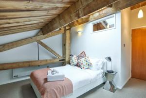 1 dormitorio con cama blanca y techo de madera en Wild Roses Serviced Apartments - ExCel Warehouse 1, en Londres