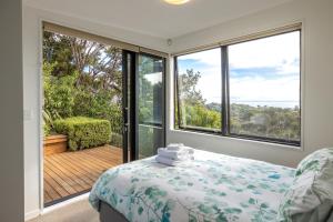 a bedroom with a bed and a large window at Hekerua Heights - Stay Waiheke in Oneroa