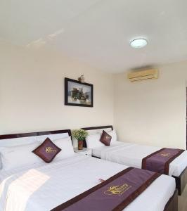 two beds in a room with white walls at Canary Hotel Hue in Hue