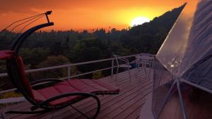 een stoel op een terras met de zonsondergang op de achtergrond bij So Good Haad Rin Resort in Haad Rin