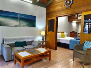 ein Wohnzimmer mit einem Bett, einem Sofa und einem Tisch in der Unterkunft Beachside Cottage - A Private Peaceful Hidden Gem 50m to Beach in Nelly Bay