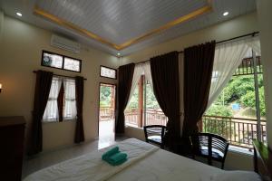 a bedroom with a bed and a balcony with windows at Ida Guest House & Restaurant in Bukit Lawang