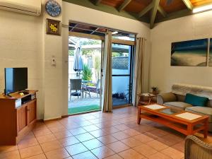een woonkamer met een bank en een tv bij Beachside Cottage - A Private Peaceful Hidden Gem 50m to Beach in Nelly Bay
