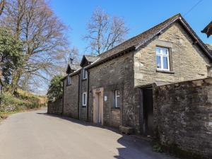 an old stone house with a road next to it at Boxwood Cottage in Troutbeck