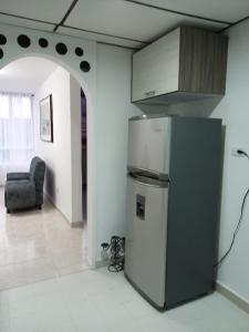 a kitchen with a refrigerator and a chair in a room at Lindo y acogedor apto cerca Mall Hospitales U Autónoma in Manizales