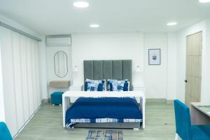 a bedroom with a white bed with blue pillows at Aparta suite tequendama in Cali