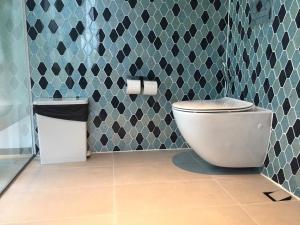 a bathroom with a toilet and a tiled wall at Phoenix Pool Villa Phu Quoc in Phú Quốc