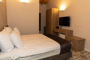 a bedroom with a bed with white pillows and a television at Saint Jacob Hotel in Nazareth