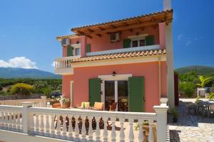 a pink house with green shutters and a balcony at Iliachtides Villas in Karavomylos