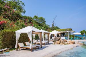 a group of umbrellas and chairs next to a pool at Casa Marina Resort in Quy Nhon