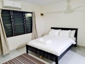 a bedroom with a bed with white sheets and a window at Masters 2 Bedroom Apartment Westfield in Nadi