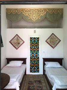 a room with two beds and a window in it at Khan Rooms in Bukhara